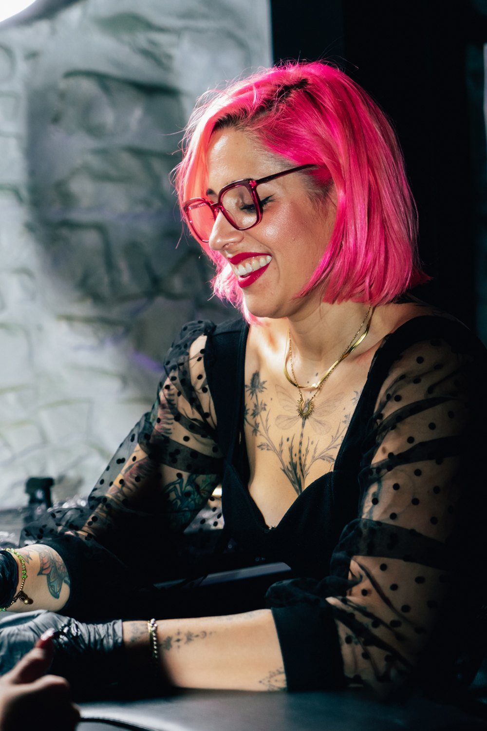 Retrato de una tatuadora de cabello rosa trabajando en su estudio