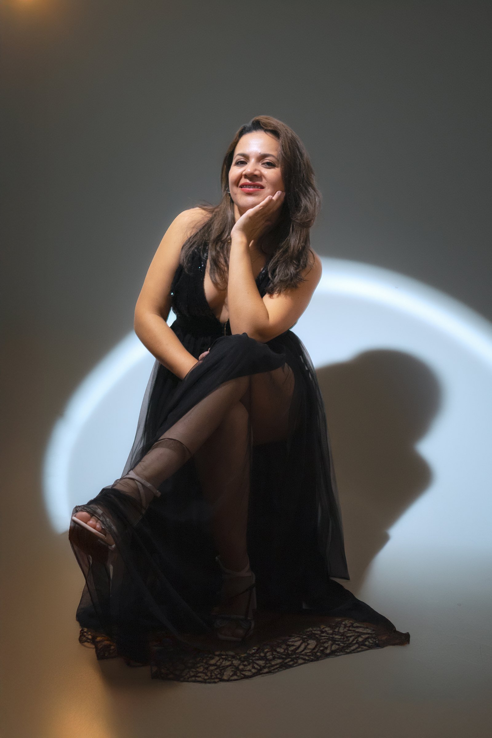 Retrato editorial de una mujer con vestido negro dentro de un círculo de luz
